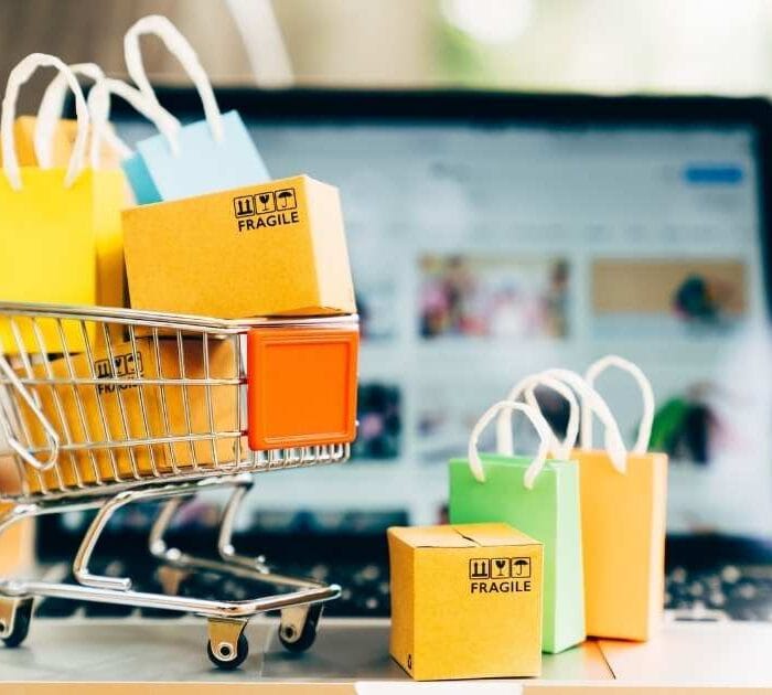 ERP pienelle yritykselle auttaa kauppiaan arkea. Ostoskärryissä on ostoskasseja ja pahvilaatikoita.